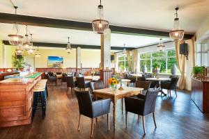 een restaurant met tafels, stoelen en ramen bij Hotel Martensplek in Tiendeveen