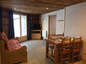 a dining room with a table and chairs and a television at La Datcha*** 4-5 personnes in Bonneval-sur-Arc