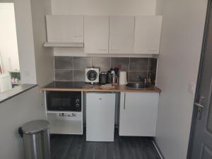 a small kitchen with white cabinets and a sink at Calme 2 Pièces en Duplex in Aufferville