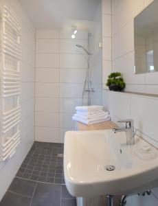 ein weißes Badezimmer mit einem Waschbecken und einem Spiegel in der Unterkunft Boardinghouse Jungwirth-Wohnzeit in Demling