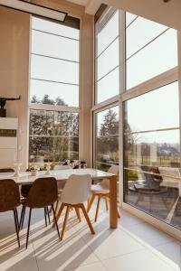 - une salle à manger avec une table, des chaises et de grandes fenêtres dans l'établissement Le Piano Blanc, à Wiesme