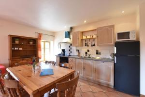 a kitchen with a wooden table and a black refrigerator at Serendipity For All Apartments in Saint Die