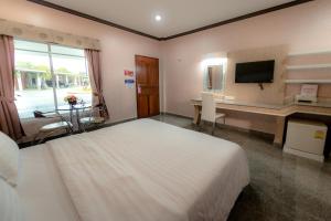 a bedroom with a bed and a desk and a television at Martina Hotel Surin in Surin