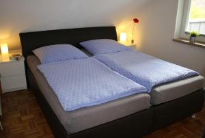 Una cama con sábanas azules y almohadas en un dormitorio en Ferienwohnung-Familie-Baasch en Embsen