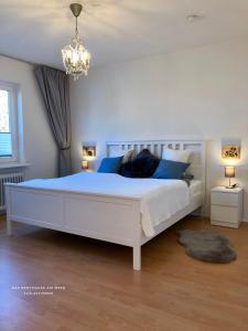 una camera da letto con un grande letto bianco con cuscini blu di Das Penthouse am Meer - Logenplatz an der Förde - a Glücksburg
