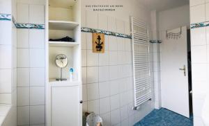 e bagno con pareti bianche piastrellate e doccia. di Das Penthouse am Meer - Logenplatz an der Förde - a Glücksburg