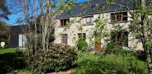 une maison en briques blanches avec des arbres devant elle dans l'établissement Les Jardins du Cloestro, à Kervignac