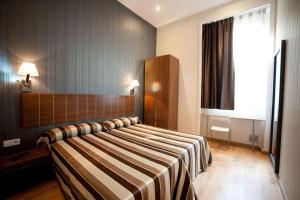 Un dormitorio con una cama con una manta a rayas. en Hostal Bcn 46, en Barcelona