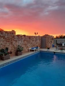 a swimming pool with a sunset in the background at Gizimina B&B by VeroSole in Xagħra