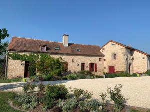 a large stone building with red doors in a yard at La Troliere in Autry-Issards