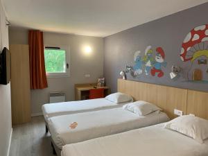 シャンブレー・レ・トゥールにあるinitial by balladins Tours Sudのベッド2台が備わる客室で、壁には絵画が飾られています。
