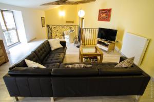 a living room with a black leather couch at La Bégude D'Amalthée in Vernay