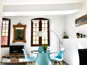 a living room with a glass table and blue chairs at La Maison du Courtil, Pistache-Chocolat in Moustiers-Sainte-Marie