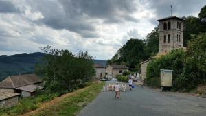 a group of people walking down a street with a church at La Bégude D'Amalthée in Vernay