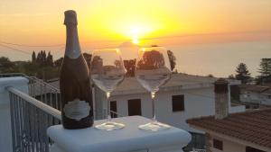 eine Flasche Wein und zwei Gläser auf dem Tisch mit Sonnenuntergang in der Unterkunft Appartamenti Borgo Panoramico n.1 in Tropea