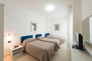 a room with three beds and a flat screen tv at Grand Hotel Adriatico in Montesilvano