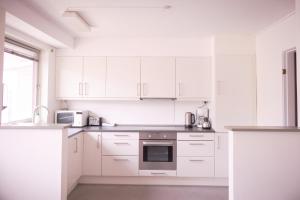 a white kitchen with white cabinets and a sink at Nattoralik in Aasiaat