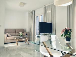 sala de estar con mesa de cristal y TV en Domus Apartamentos Granada con parking gratuito en pleno centro, en Granada