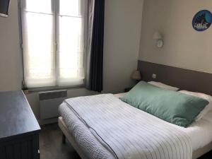 a bedroom with a bed with a green pillow at Le Cottage in Villers-sur-Mer