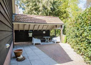 un patio con 2 sillas, una mesa y un techo en appartement - sauna - natuur - Utrecht en Soest