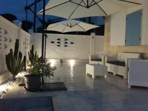 a patio with white furniture and umbrellas at night at La Dimora Sipontina in Manfredonia