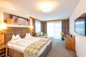 ein Hotelzimmer mit einem großen Bett und einem Fernseher in der Unterkunft Hotel Garni Melanie in Wals + 58 Fotos