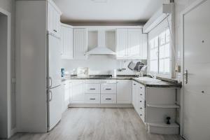 a white kitchen with white cabinets and a sink at Chalet pareado a 5 minutos andando de la playa in La Garita