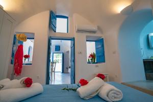 a bedroom with two towels on a bed with red flowers at Bonita Santorini Cave in Éxo Goniá