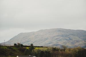 a mountain in the distance with a house in the foreground at corby house in Ardara