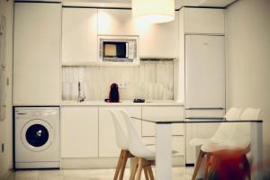 cocina con armarios blancos y lavadora en Domus Apartamentos Granada con parking gratuito en pleno centro en Granada