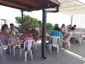 a group of people sitting at tables on a patio at La Caletta in Santa Flavia