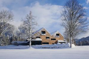 ein Backsteinhaus im Schnee mit zwei Bäumen in der Unterkunft pure mountain BASE in Erpfendorf