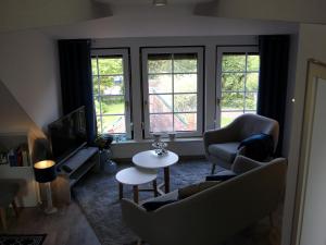 a living room with a couch and chairs and a tv at up Stuuv in Greetsiel