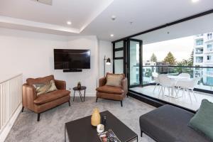 a living room with a couch and chairs and a tv at Ocean Eleven 22 in Mount Maunganui