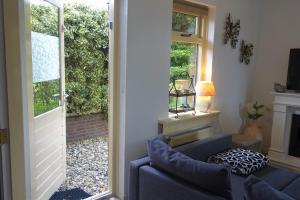 uma sala de estar com um sofá azul e uma porta de vidro deslizante em De Aardigeyt em Giethoorn