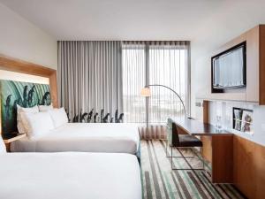 a hotel room with two beds and a desk at Novotel Auckland Airport in Auckland