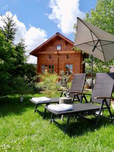 - une table de pique-nique, 2 chaises et un parasol en face d'une cabine dans l'établissement Ferienhaus Kleine Pfalz, à Ranschbach