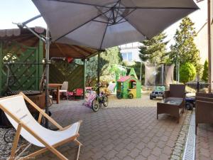 a patio with an umbrella and chairs and a playground at Pensjonat U Janiny Bolesławiec in Bolesławiec