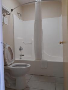 a white bathroom with a toilet and a shower at DEERFIELD INN in Parsons