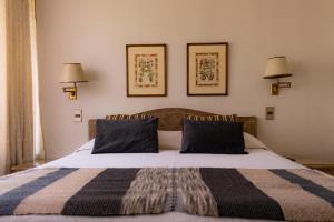 a bedroom with a bed with two lamps on the wall at Alessandria Apart - Coronel Pereira in Santiago