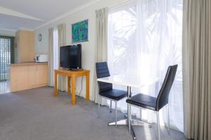Euroa Motor Inn في اوروا: غرفة معيشة مع طاولة وكراسي وتلفزيون