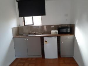 una pequeña cocina con fregadero y nevera. en Birch Motel Tocumwal en Tocumwal