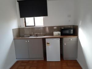 a small kitchen with a sink and a refrigerator at Birch Motel Tocumwal in Tocumwal