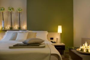 een slaapkamer met een wit bed, groene muren en kaarsen bij Albergo D'italia in Chivasso +8 foto's