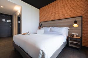 a bedroom with a large white bed with a brick wall at ONOMO Airport Casablanca in Casablanca