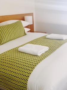 two beds with yellow and white sheets and pillows at Red Earth Motel in Broken Hill
