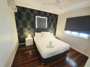 a bedroom with a white bed with a black and white wall at 2 bedroom cottage in Townsville