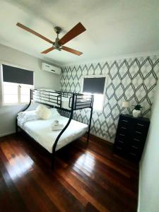 a bedroom with a bed and a ceiling fan at 2 bedroom cottage in Townsville