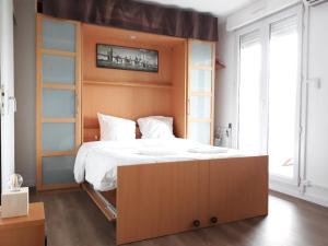 a bedroom with a large bed with a wooden headboard at Studio Santa Monica - Climatisé - Piscine - Parking in Toulouse