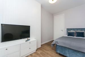 a bedroom with a bed and a flat screen tv at Blue Rentyear Apartments in Gdańsk